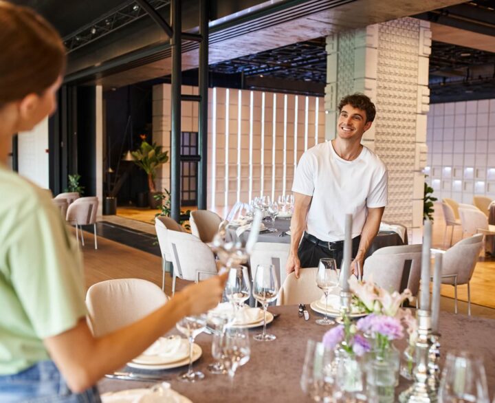 smiling-man-near-festive-tables-looking-at-woman-on-blurred-foreground-banquet-organizers-at-work.jpg
